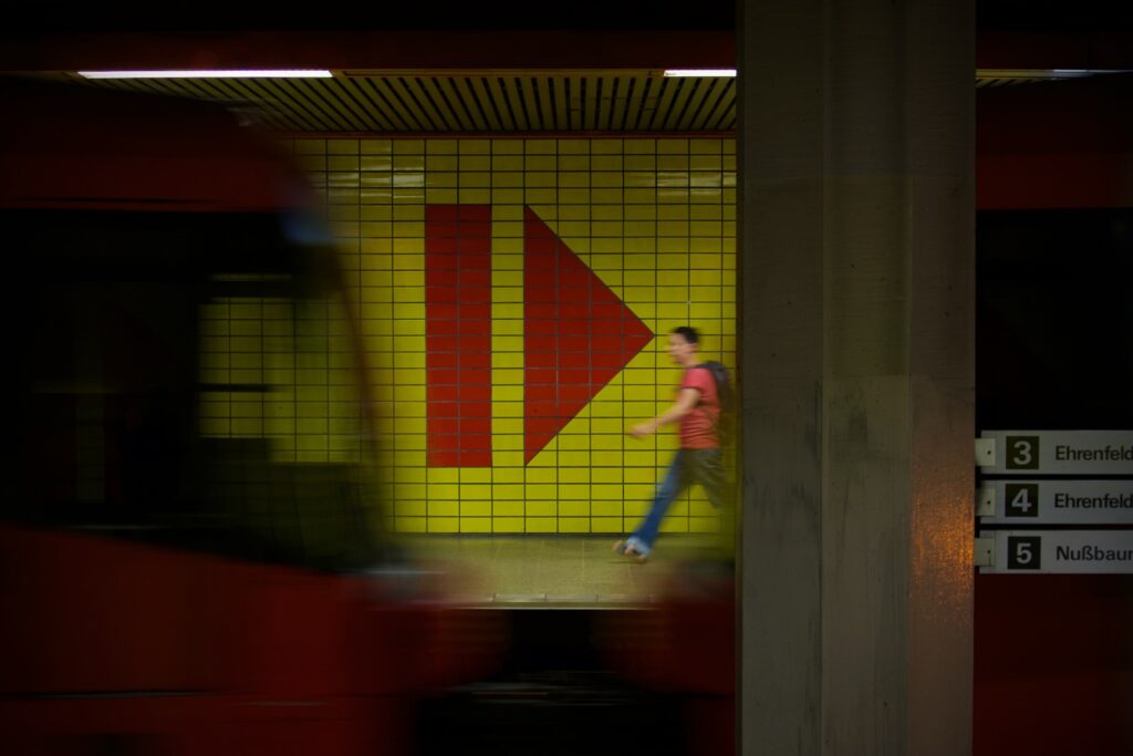 Bild einer einfahrenden U-Bahn in die Haltestelle mit einer gehenden Person.